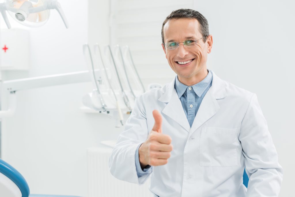 Dentist showing thumb up in modern dental clinic