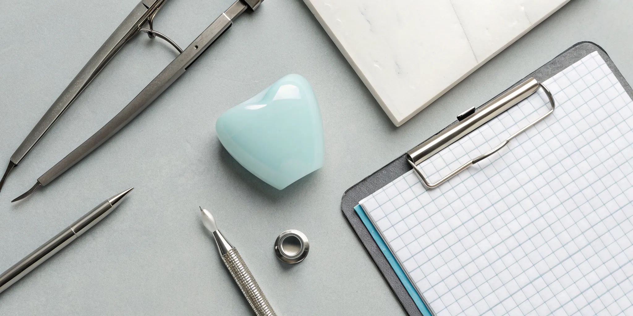 Emax crown model and dental tools on a clipboard representing the lab bill cost for dentists.
